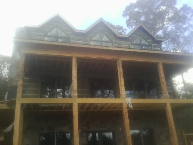 Dormers and porch framing on a large log home under construction — Roof Coating work by our crew in Glen Arm