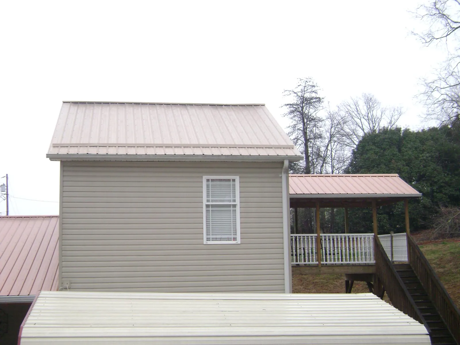 Tan metal roofs on a two story addition and attached porch, from a Roof Replacement job in Glen Arm