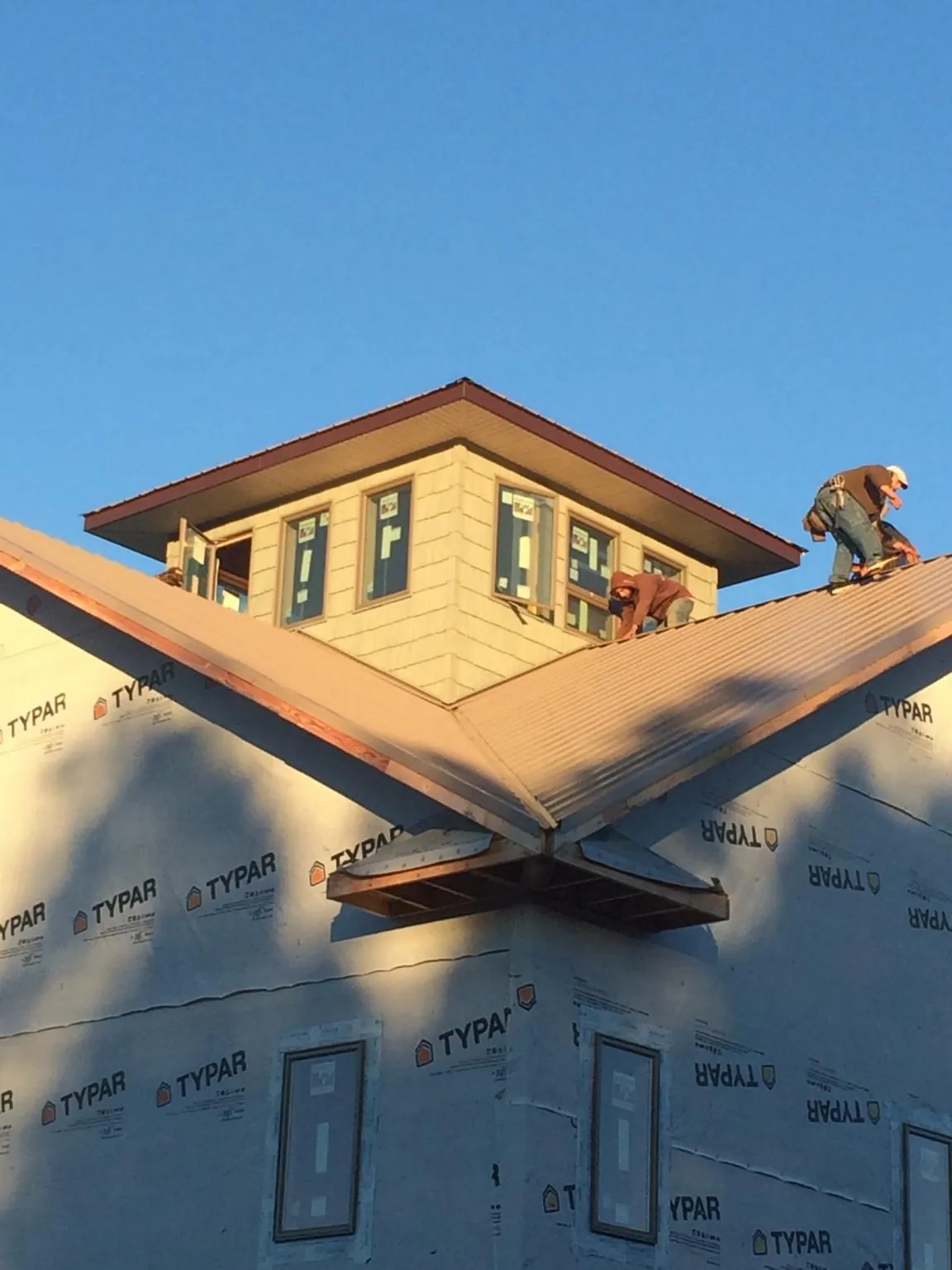 Roofers working around a rooftop cupola on a new metal roof at sunset — Roof Waterproofing in Glen Arm by Roofing Brothers